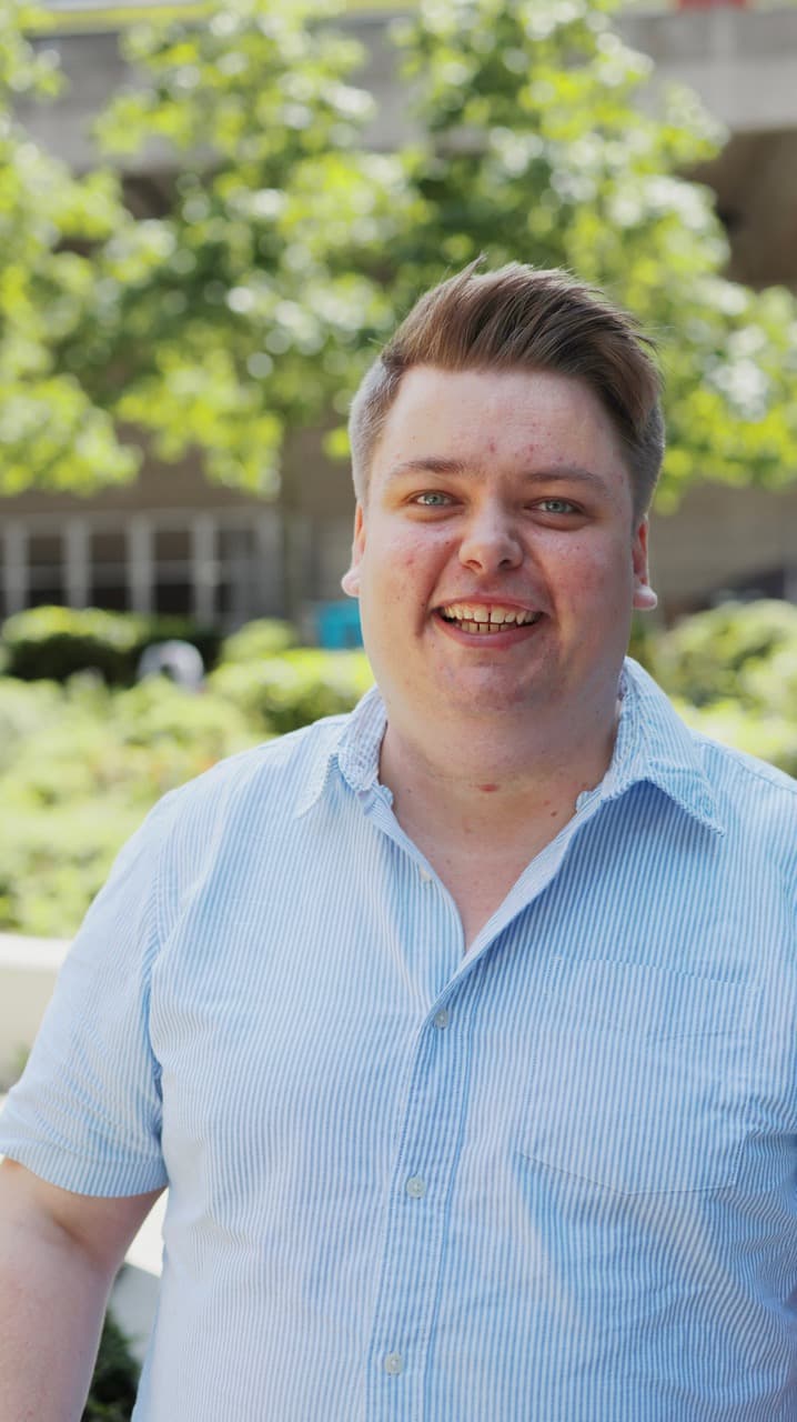 Thomas Roper smiling outdoors in a blue shirt